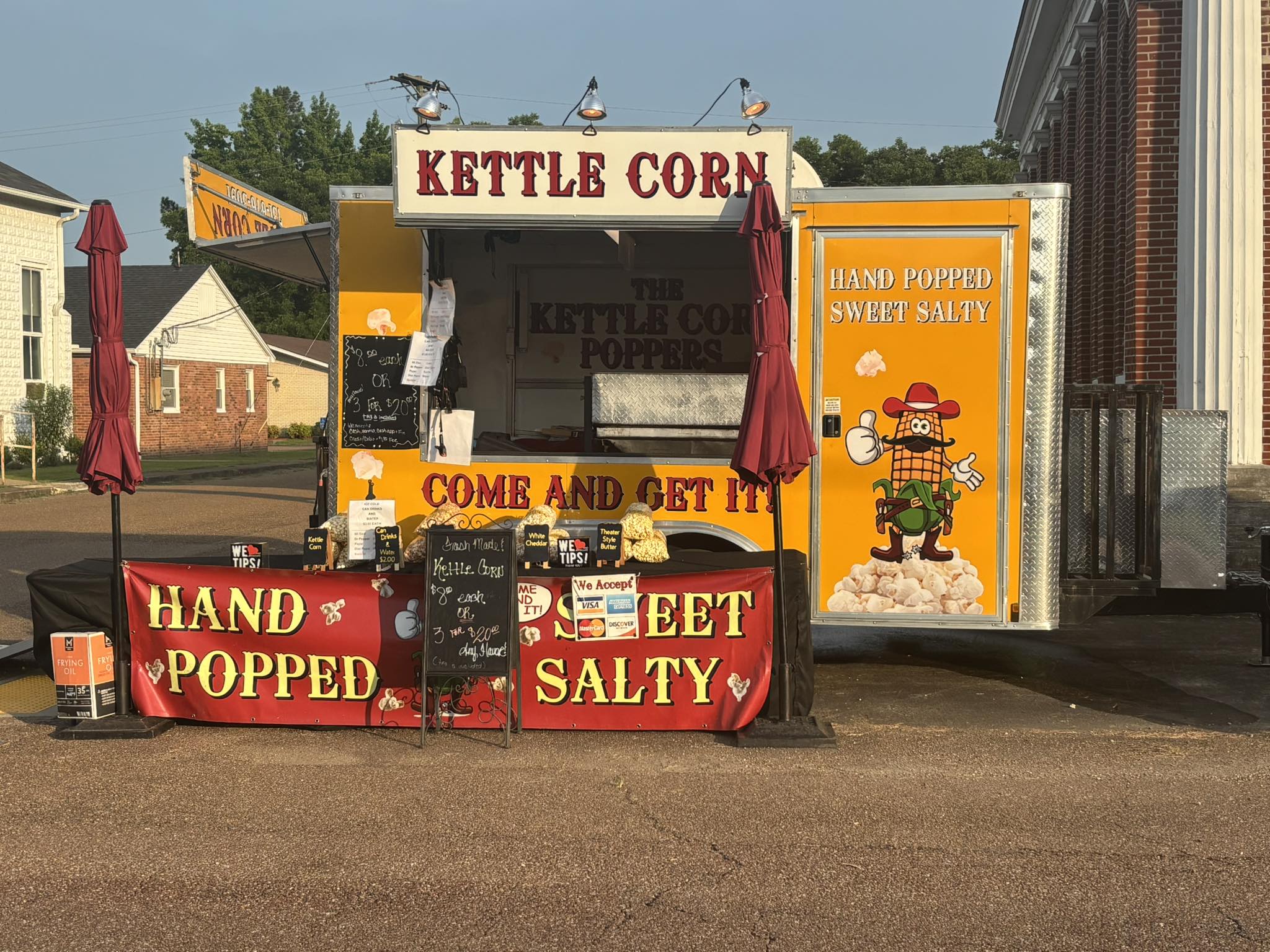 The yellow Kettle Corn Poppers trailer with red hand-popped sweet and salty banners.